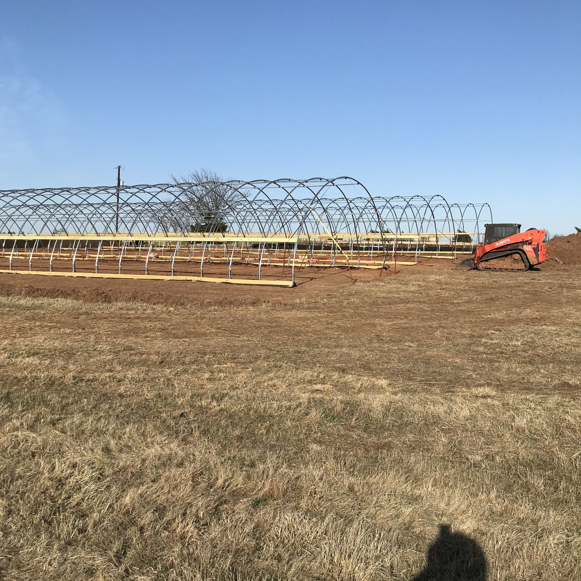 Steel hoop house frames on Oklahoma red dirt